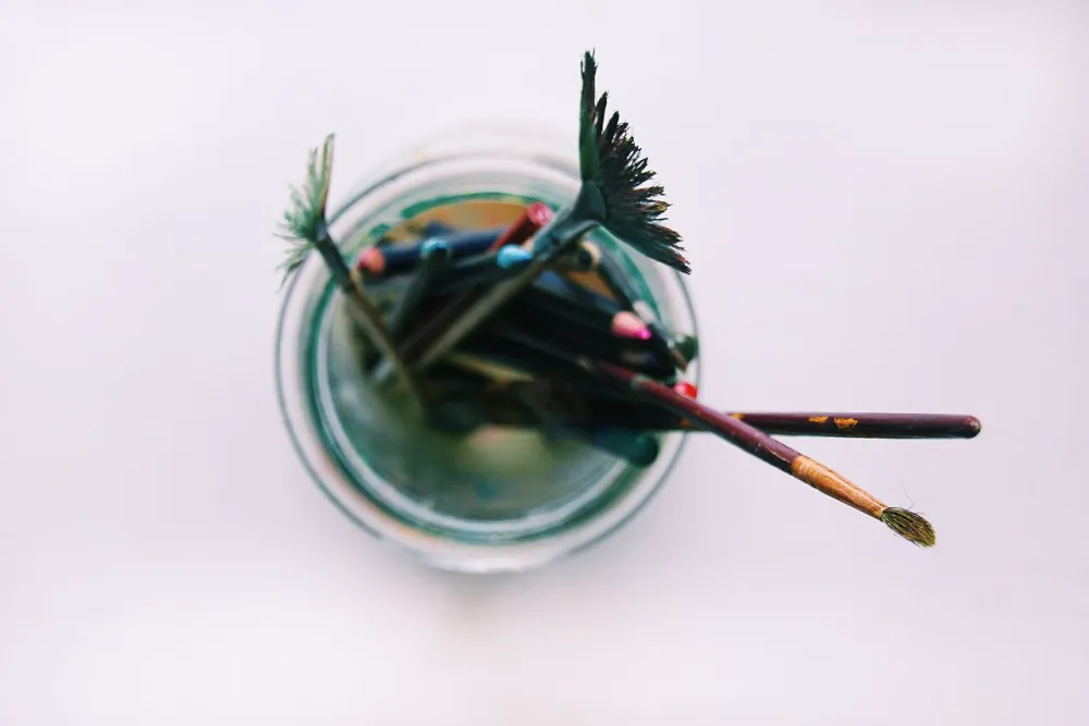 Pinsel stehen mit den Haaren nach unten in einem Wasserglas, die Haare sind verbogen