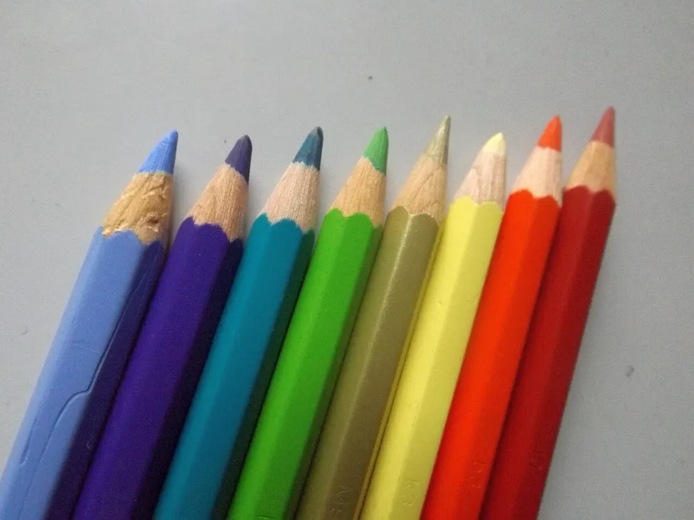 Acht angespitzte Aquarellstifte in Blau, Violett, Türkis, Grün, Gelb, Orange und Rot
